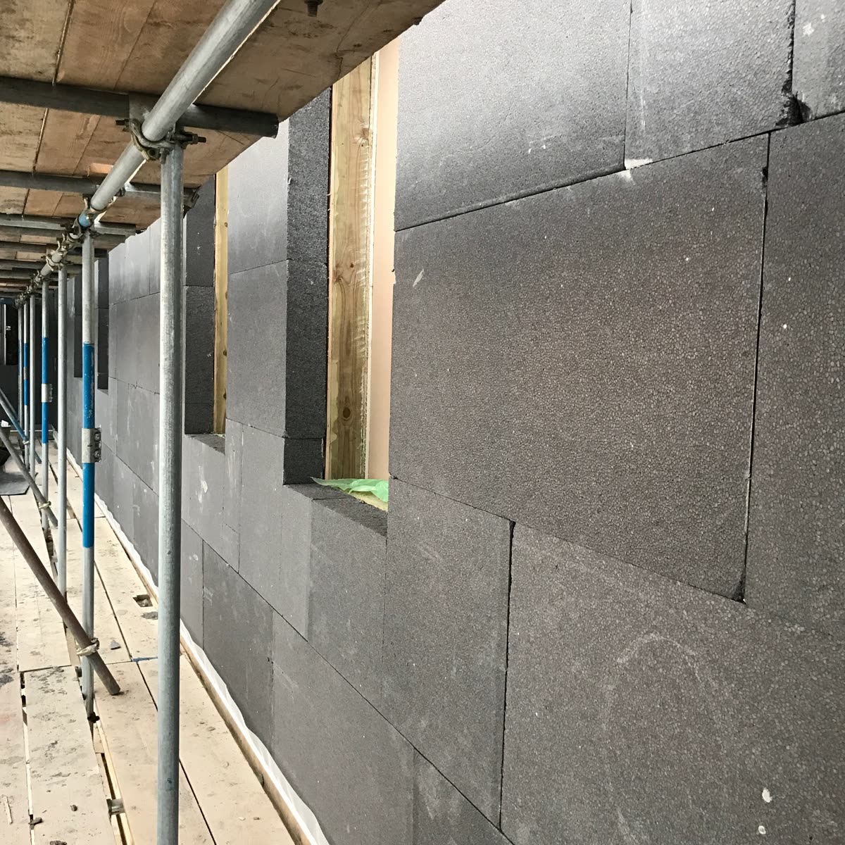 External wall insulation going on over the new frame — 140mm of expanded polystyrene, the build-up that achieves 0.18 W/m²K.